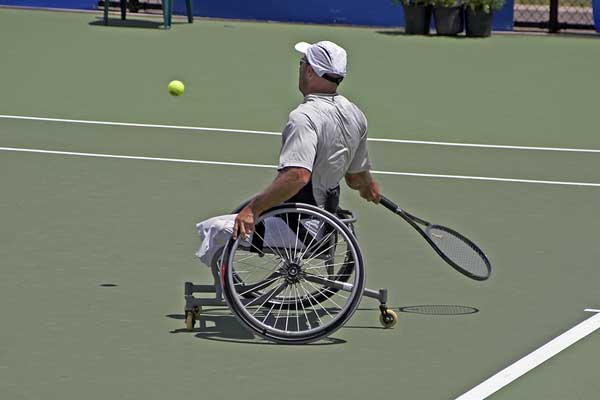 disabled man playing tennis in a wheelchair